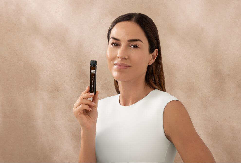 Mujer mostrando DSP-Bright Elixir, complemento alimenticio bebible con vitamina C